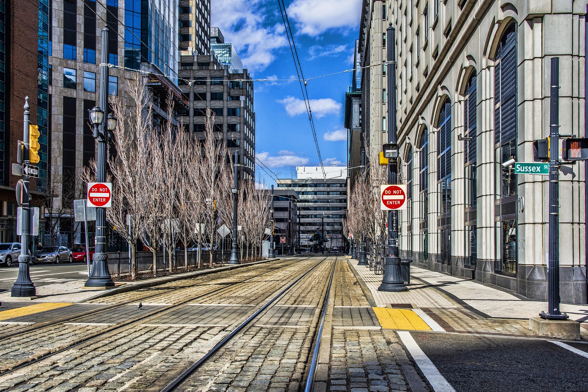 Jersey City street with light rail tracks and Manhattan skyline