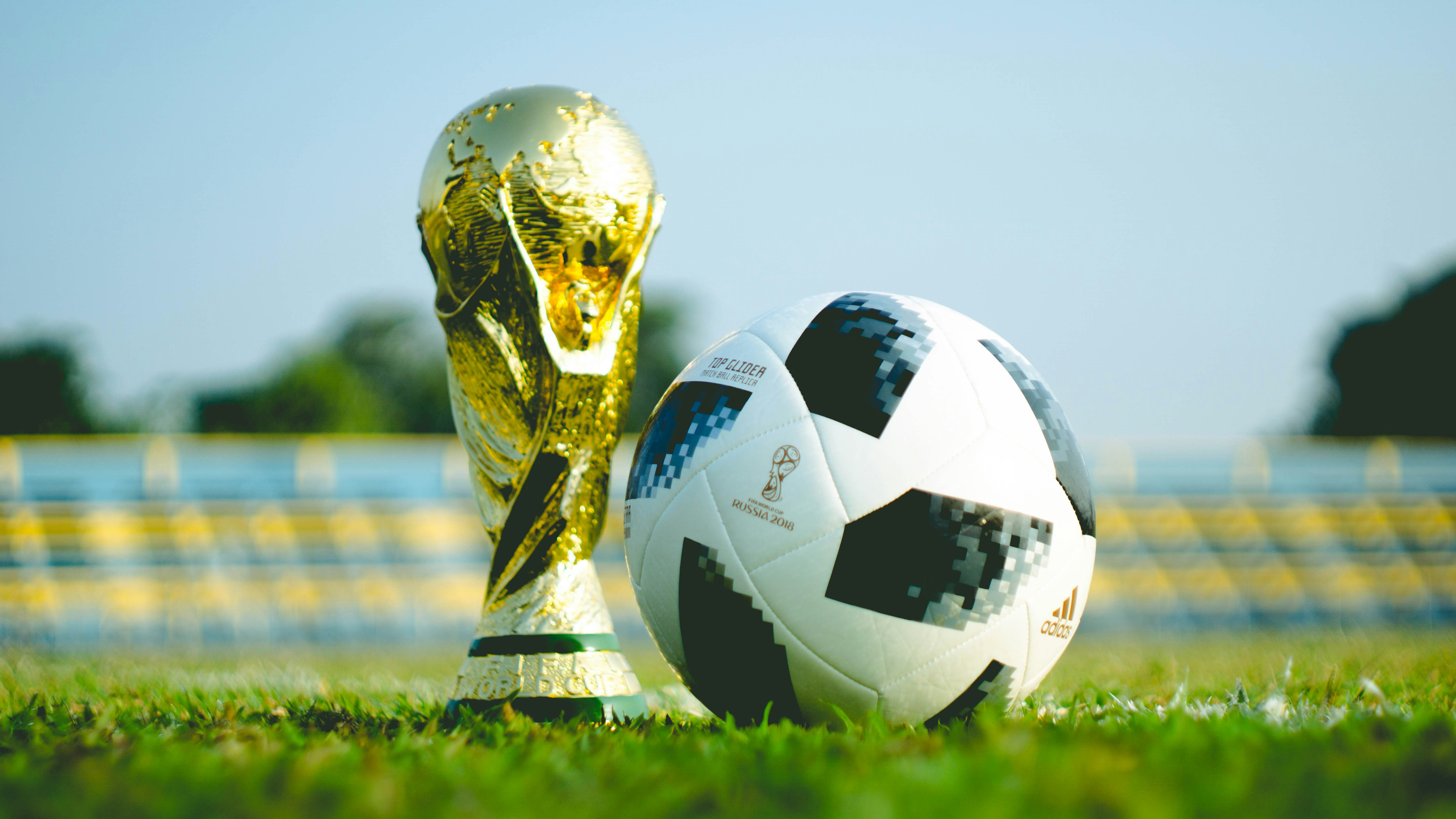 FIFA World Cup trophy and match ball on stadium pitch
