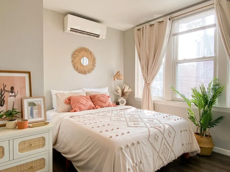 Bedroom 3 — coral pillows, woven sunburst mirror, rattan dresser, palm plant
