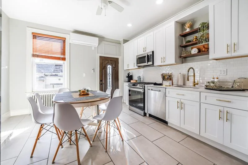 Renovated kitchen with white cabinets, gold fixtures, dining for 6